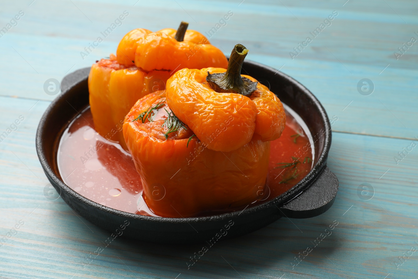 Photo of Tasty stuffed peppers on light blue wooden table, closeup