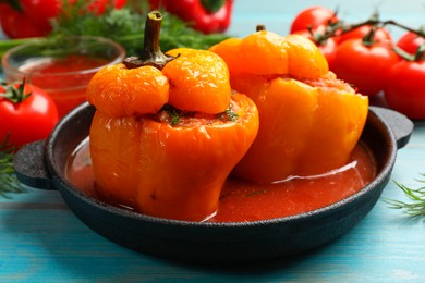 Photo of Tasty stuffed peppers and products on light blue wooden table, closeup