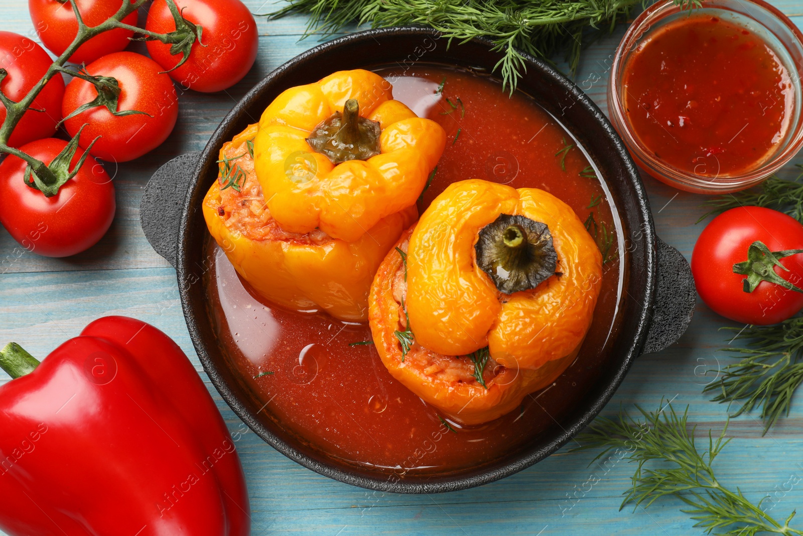 Photo of Tasty stuffed peppers and products on light blue wooden table, flat lay