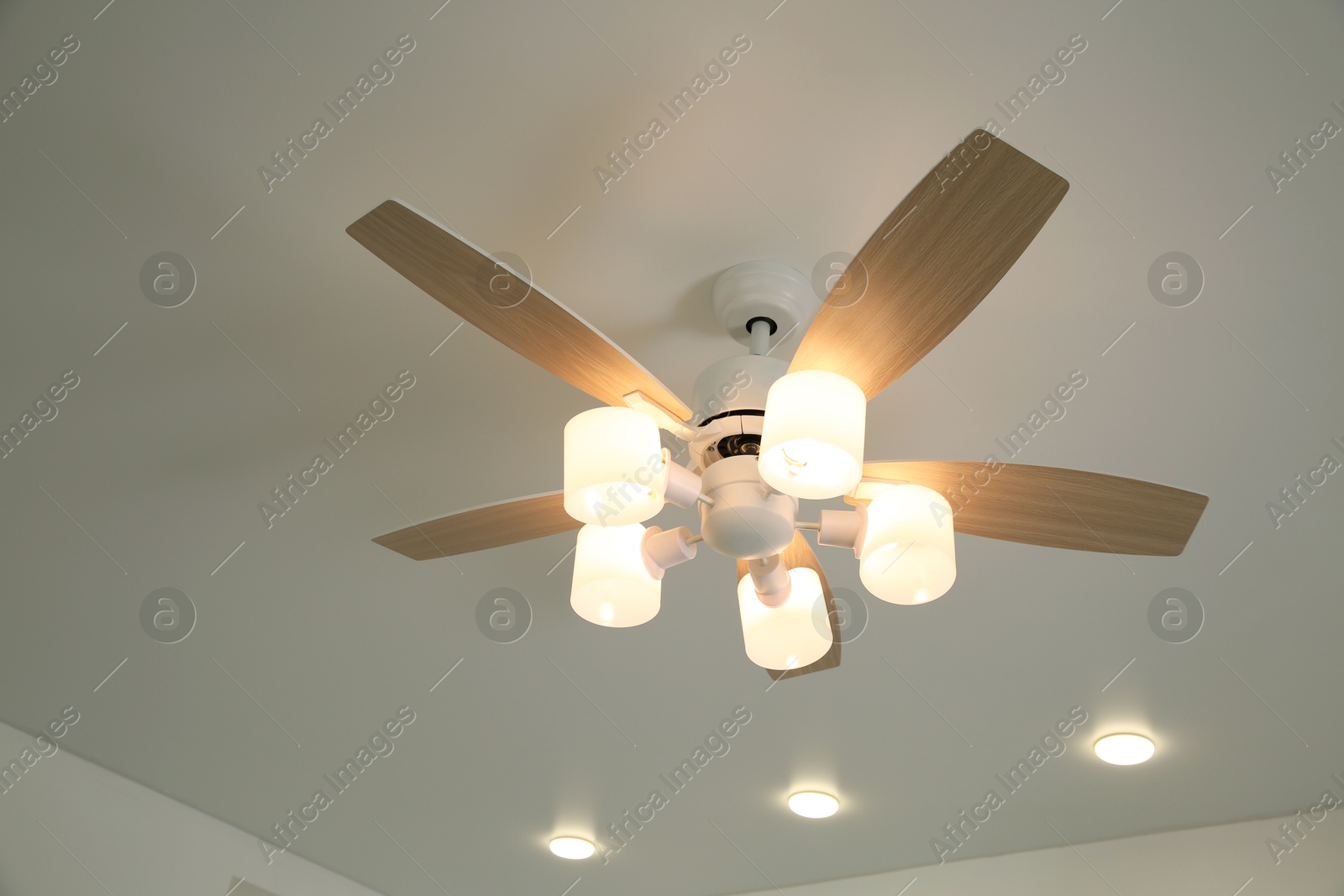 Photo of Ceiling fan with lamps indoors, low angle view