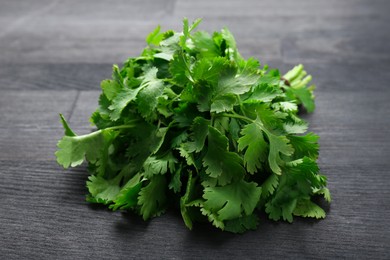 Photo of Bunch of fresh coriander on black wooden table, closeup