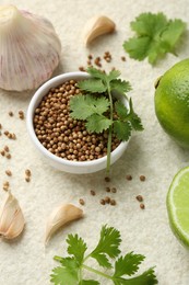 Fresh coriander leaves, dried seeds, garlic and limes on light textured table