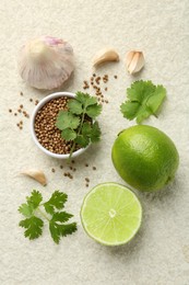 Photo of Fresh coriander leaves, dried seeds, garlic and limes on light textured table, flat lay