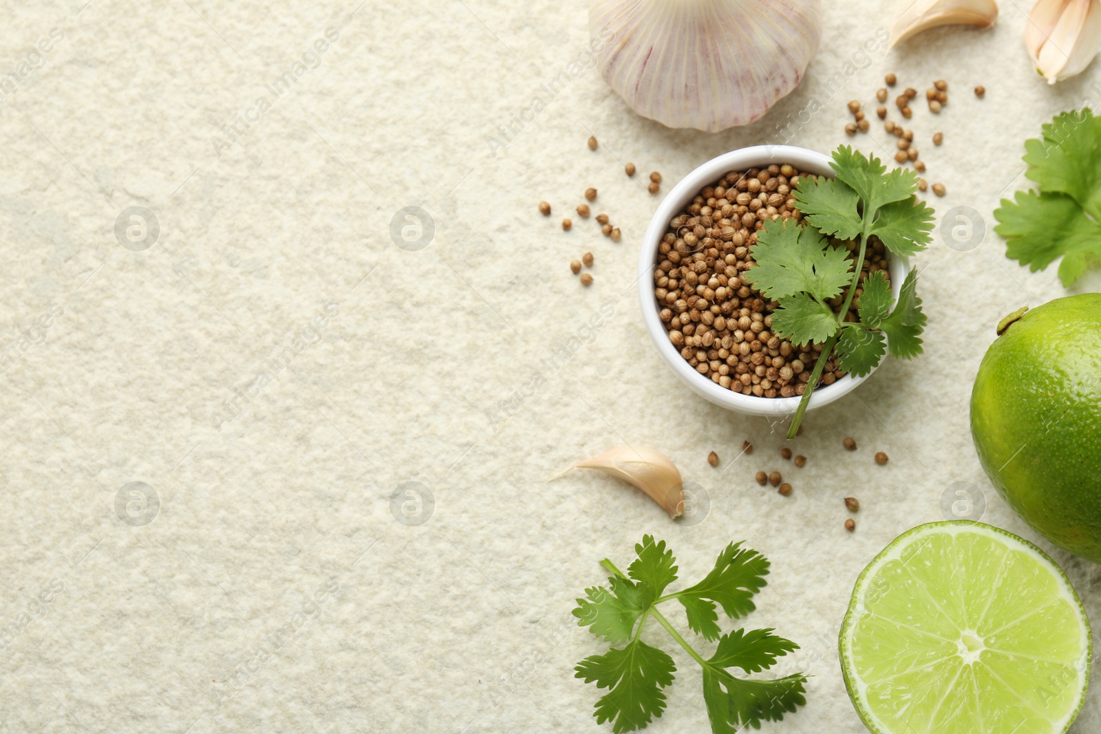 Photo of Fresh coriander leaves, dried seeds, garlic and limes on light textured table, flat lay. Space for text