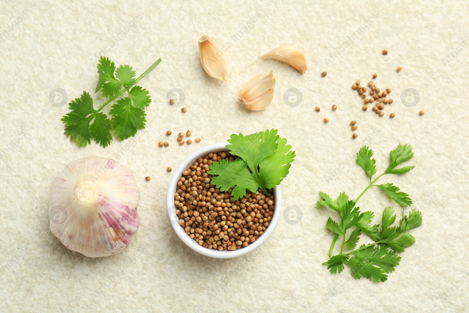 Photo of Fresh coriander leaves, dried seeds and garlic on light textured table, flat lay