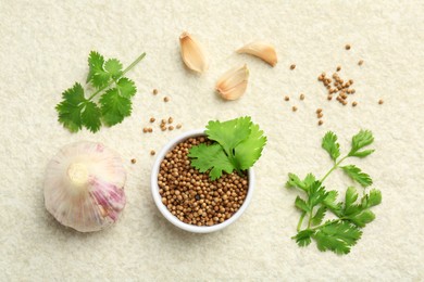 Fresh coriander leaves, dried seeds and garlic on light textured table, flat lay