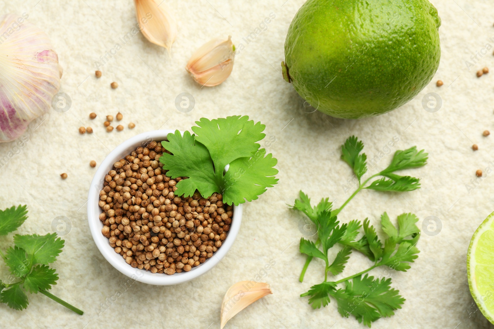 Photo of Fresh coriander leaves, dried seeds, garlic and lime on light textured table, flat lay