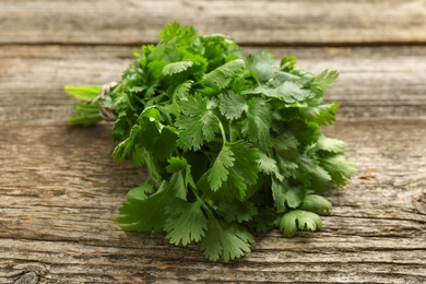 Photo of Bunch of fresh coriander on wooden table, closeup