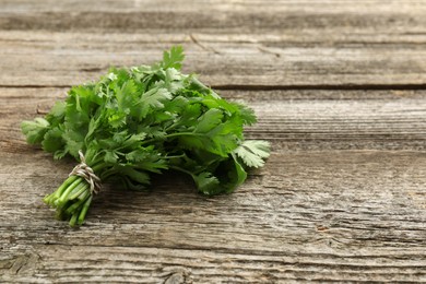 Photo of Bunch of fresh coriander on wooden table, space for text