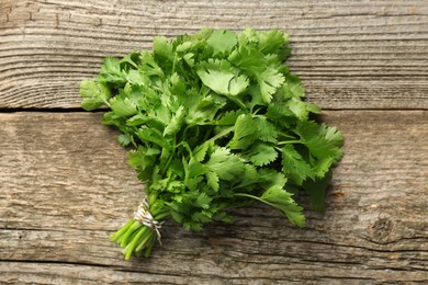 Photo of Bunch of fresh coriander on wooden table, top view