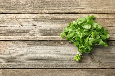 Bunch of fresh coriander on wooden table, top view. Space for text