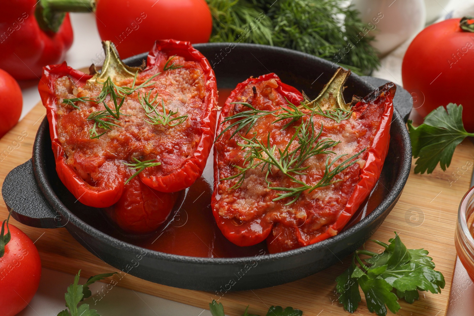 Photo of Tasty stuffed peppers in dish and ingredients on white table, closeup