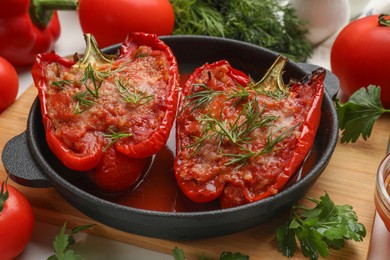 Photo of Tasty stuffed peppers in dish and ingredients on white table, closeup