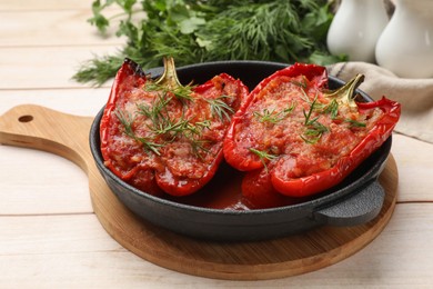 Photo of Tasty stuffed peppers in dish on white wooden table