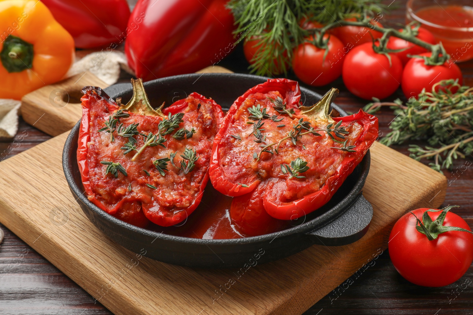 Photo of Tasty stuffed peppers in dish on wooden table