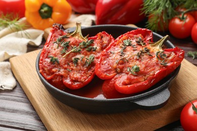 Photo of Tasty stuffed peppers in dish on wooden table