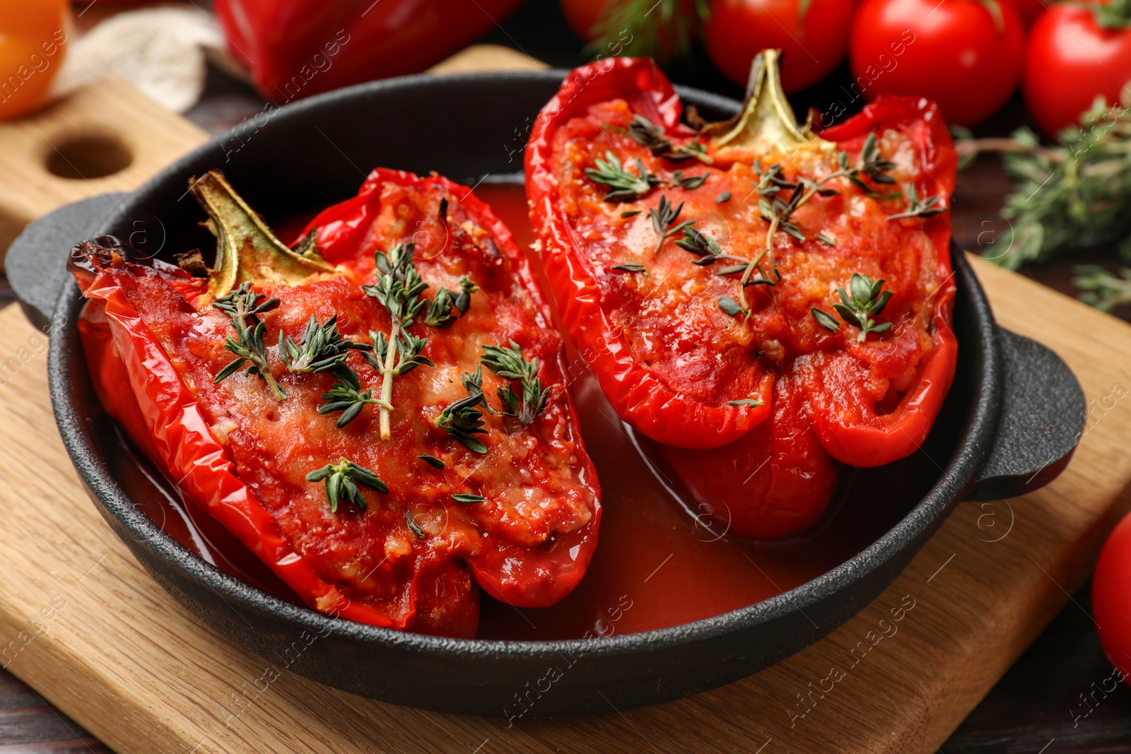 Photo of Tasty stuffed peppers in dish on wooden table, closeup