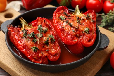 Photo of Tasty stuffed peppers in dish on wooden table, closeup