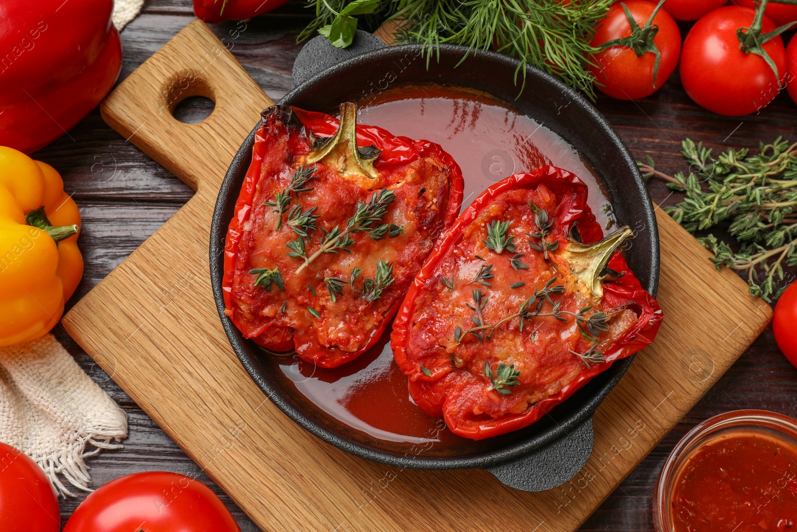 Photo of Tasty stuffed peppers in dish and ingredients on wooden table, flat lay