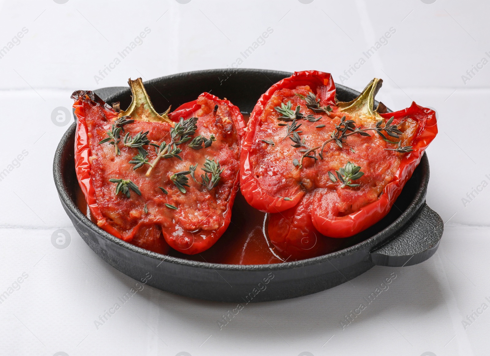 Photo of Tasty stuffed peppers in dish on white tiled table. Space for text