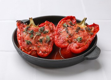 Photo of Tasty stuffed peppers in dish on white tiled table. Space for text