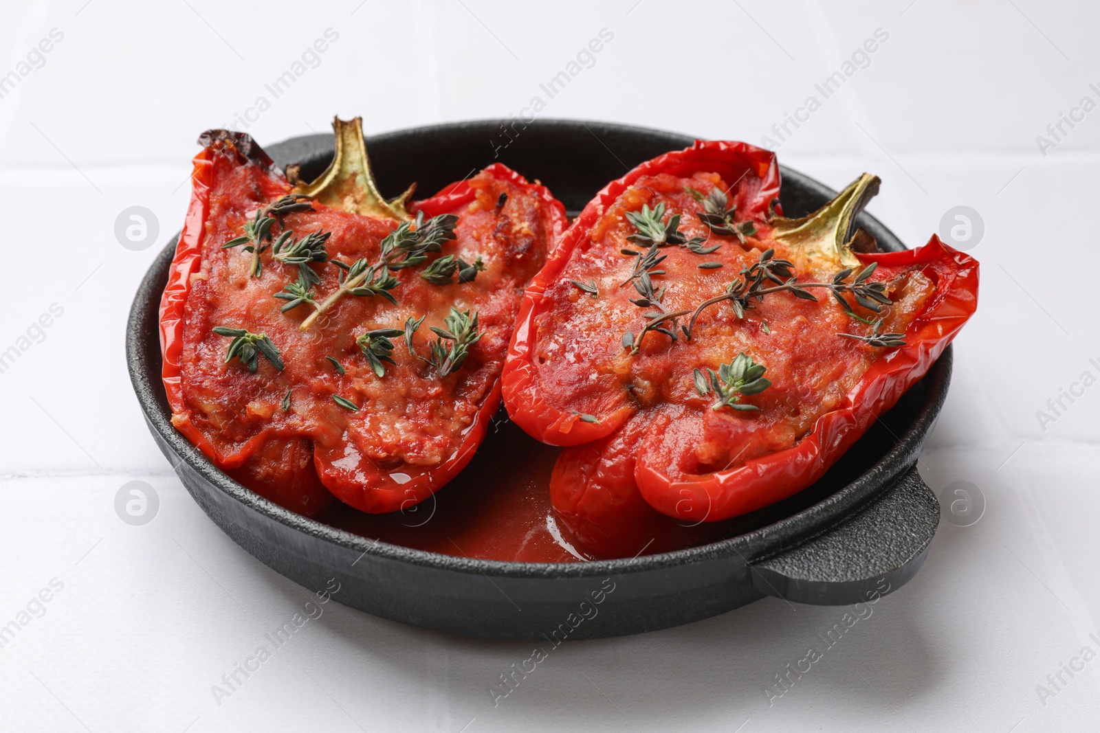 Photo of Tasty stuffed peppers in dish on white tiled table