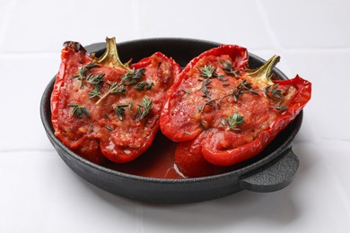 Photo of Tasty stuffed peppers in dish on white tiled table