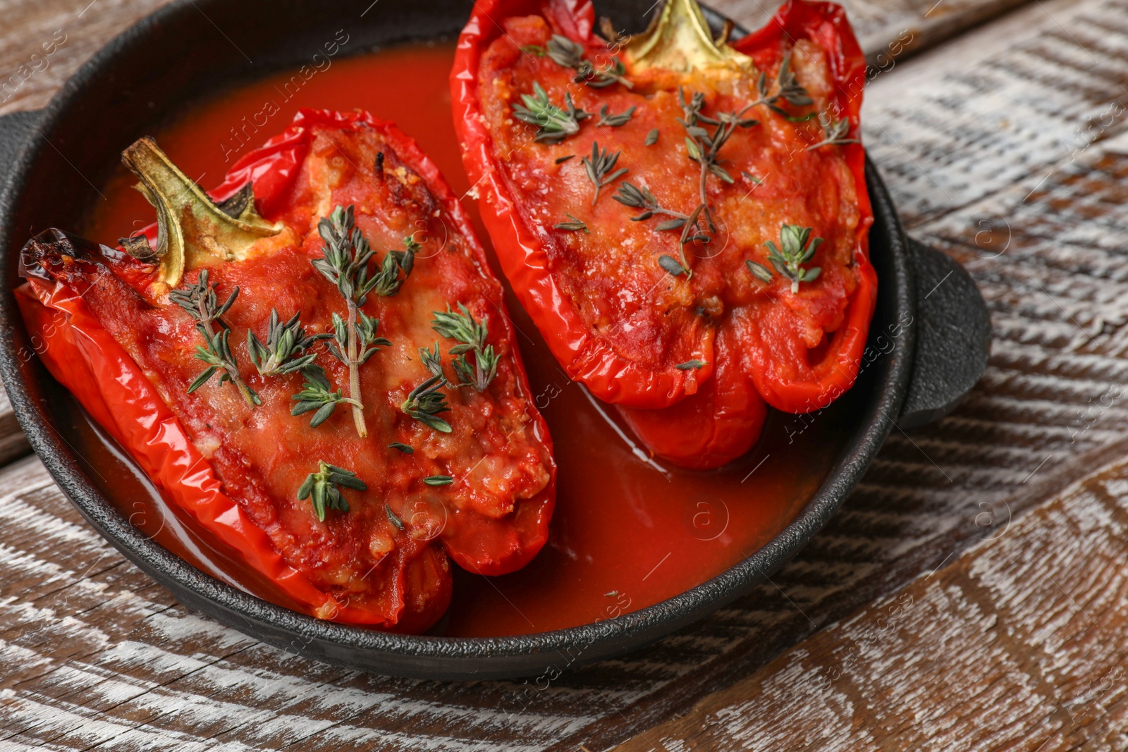 Photo of Tasty stuffed peppers in dish on wooden table, closeup