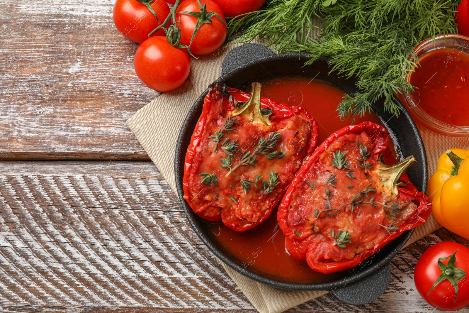 Photo of Tasty stuffed peppers in dish and ingredients on wooden table, flat lay. Space for text