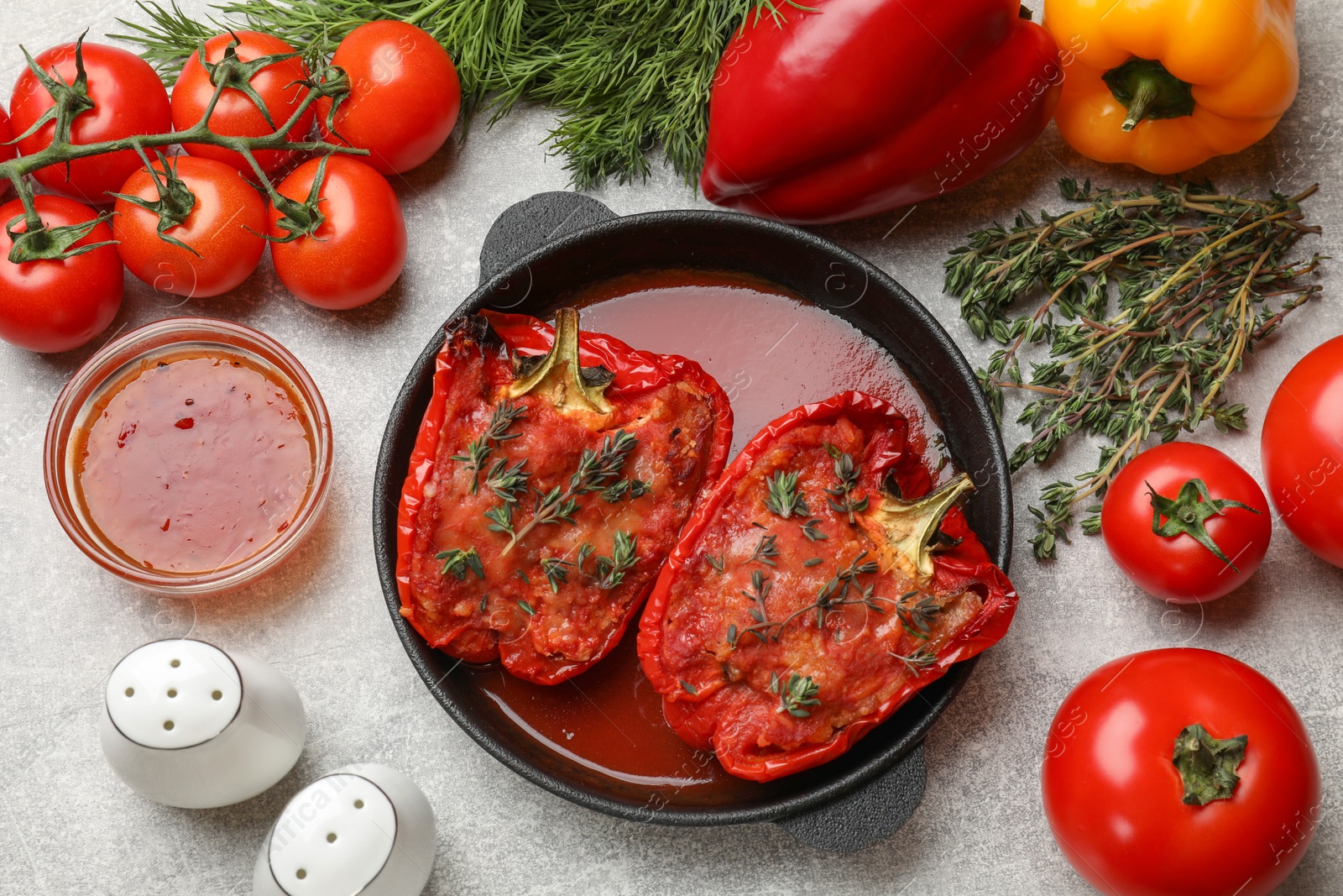 Photo of Tasty stuffed peppers in dish and ingredients on light grey table, flat lay