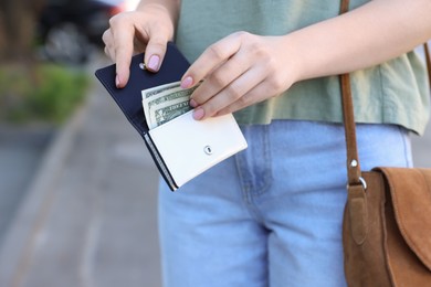 Photo of Woman holding purse with banknotes outdoors, closeup