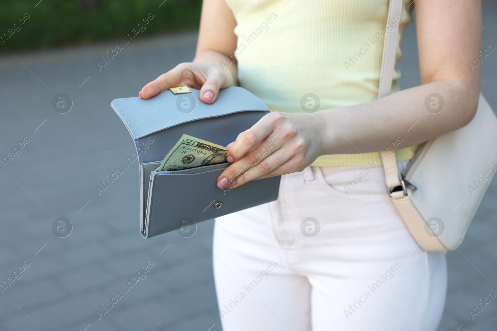 Photo of Woman holding purse with banknotes outdoors, closeup