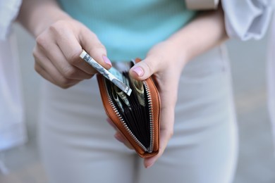 Photo of Woman holding purse with banknotes outdoors, closeup