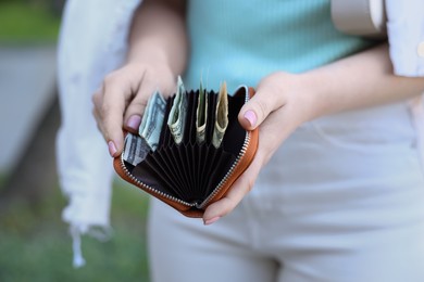 Woman holding purse with banknotes outdoors, closeup