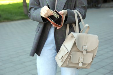 Woman holding purse with banknotes outdoors, closeup