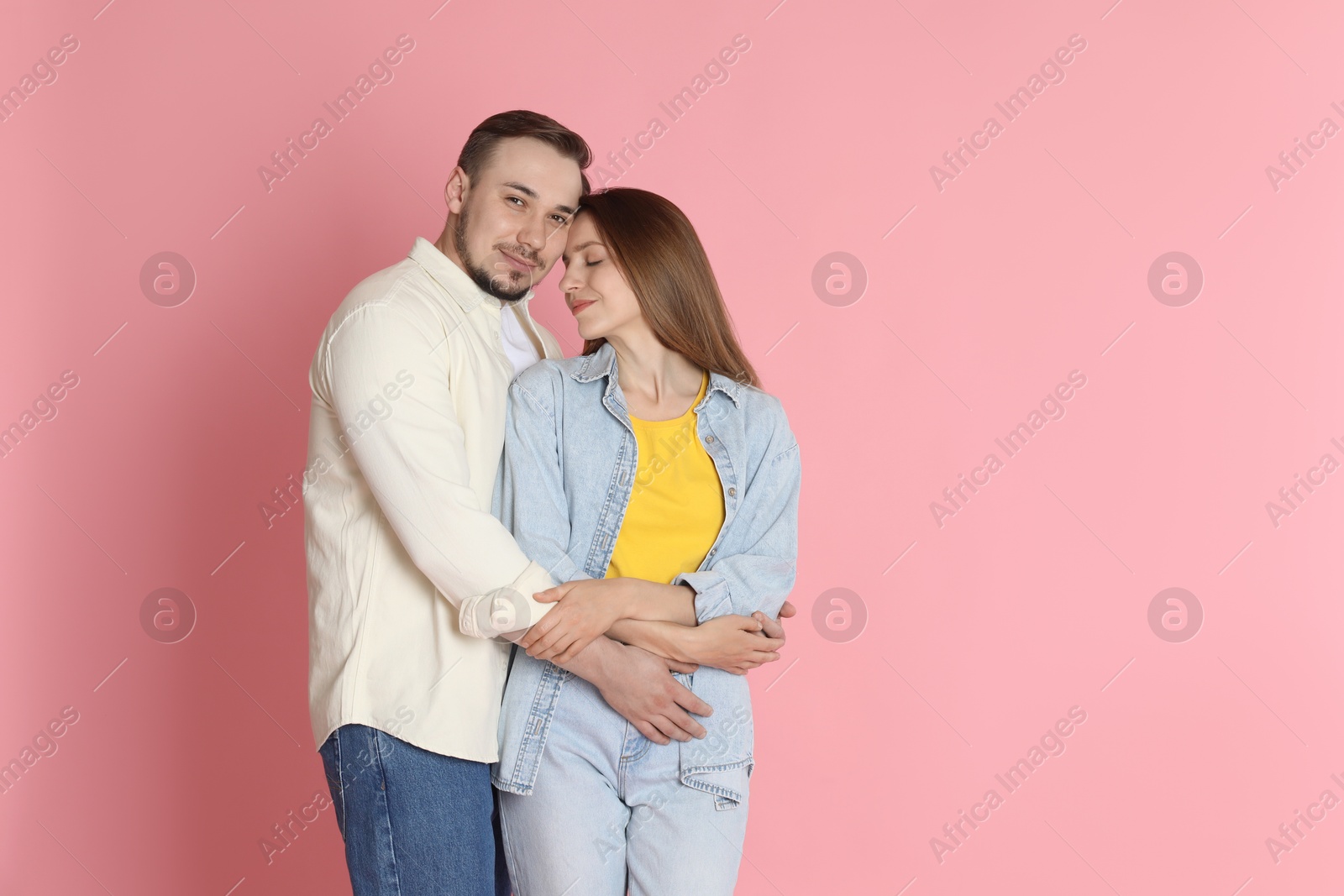 Photo of Man hugging his girlfriend on pink background. Space for text