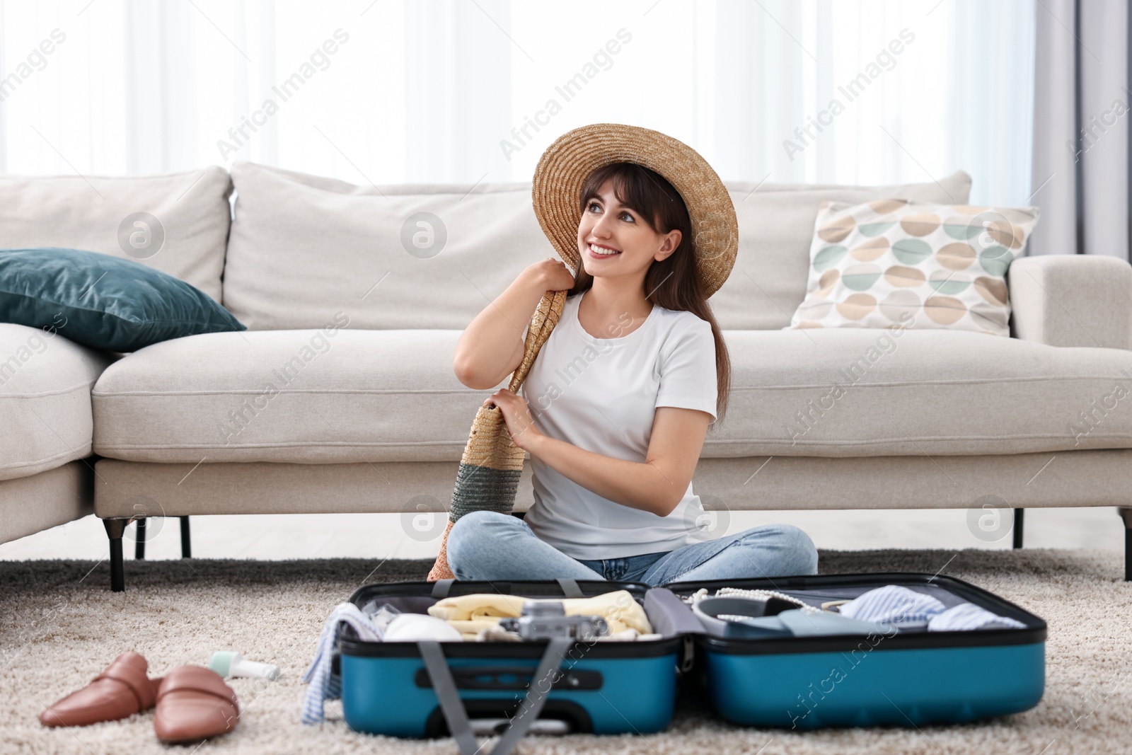 Photo of Woman packing suitcase for trip on floor indoors