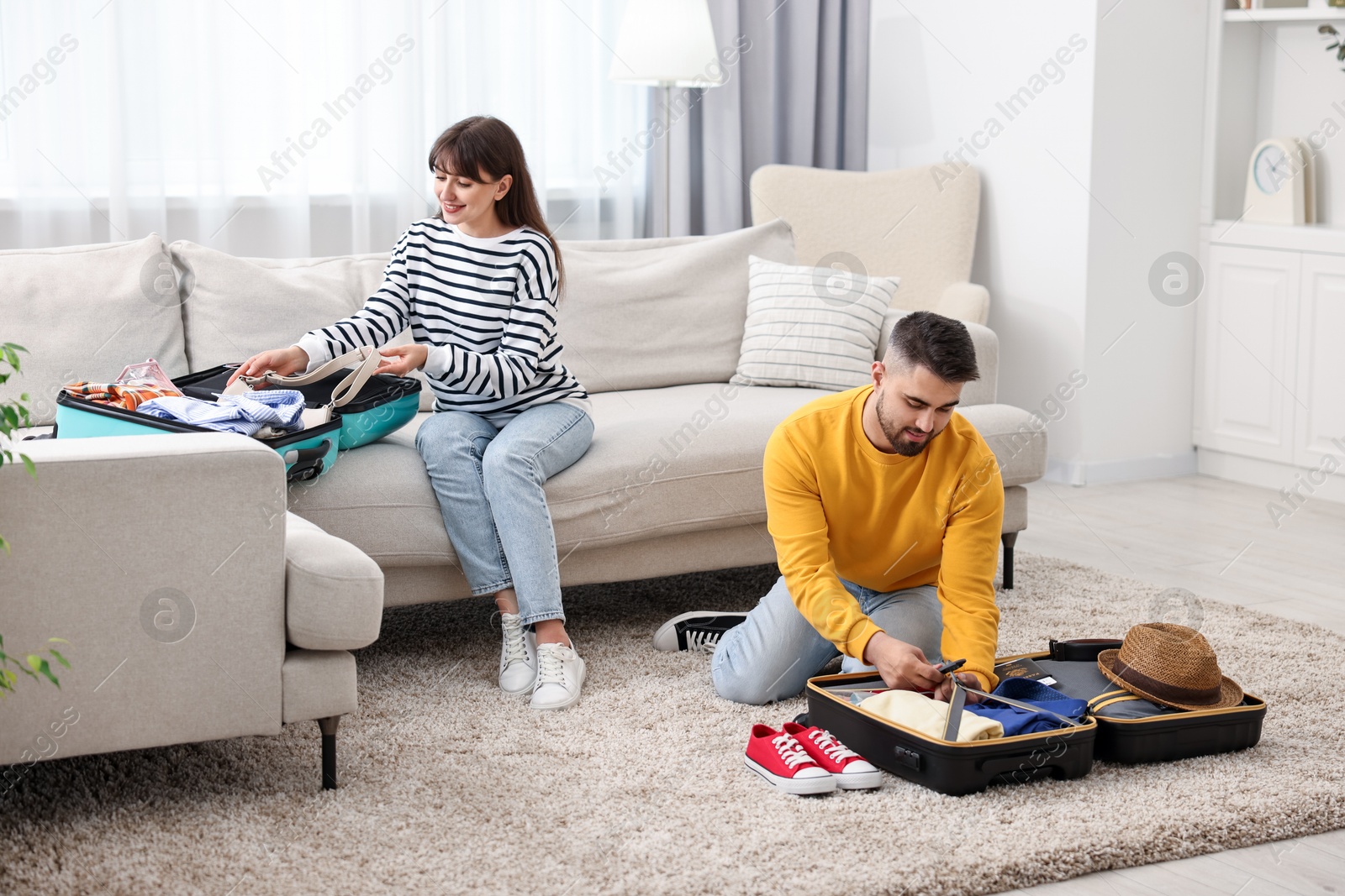 Photo of Couple packing suitcases for trip at home