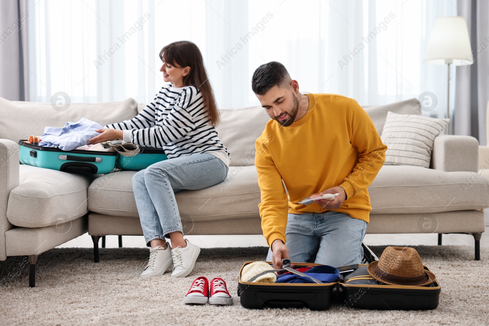 Photo of Couple packing suitcases for trip at home