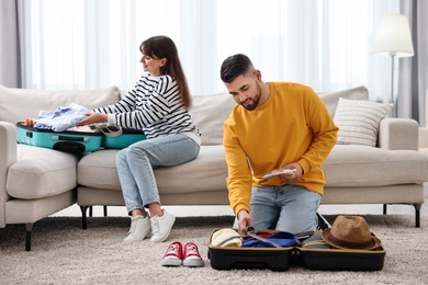 Couple packing suitcases for trip at home