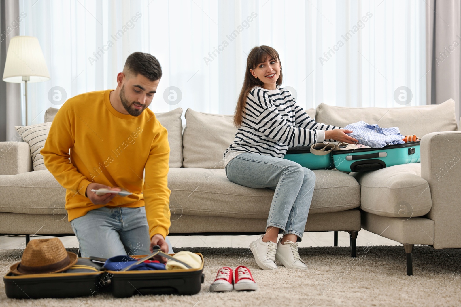 Photo of Couple packing suitcases for trip at home