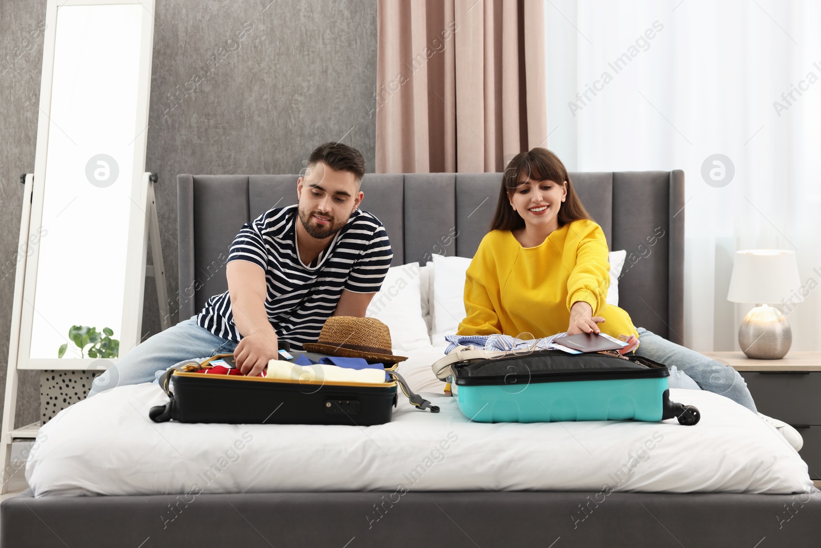 Photo of Couple packing suitcases for trip in bedroom