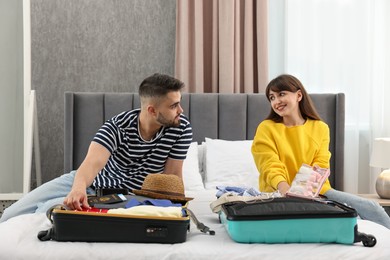 Couple packing suitcases for trip in bedroom