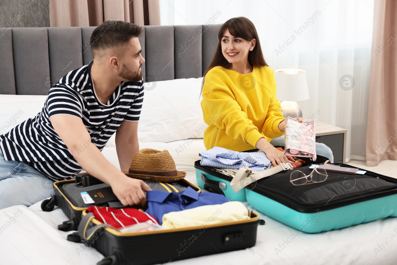 Photo of Couple packing suitcases for trip in bedroom