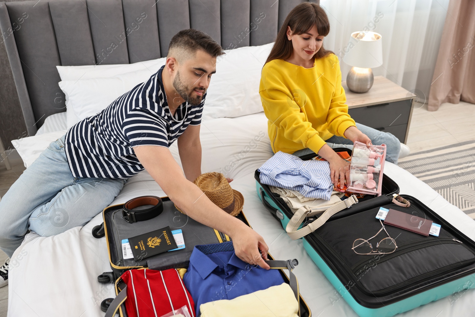 Photo of Couple packing suitcases for trip in bedroom