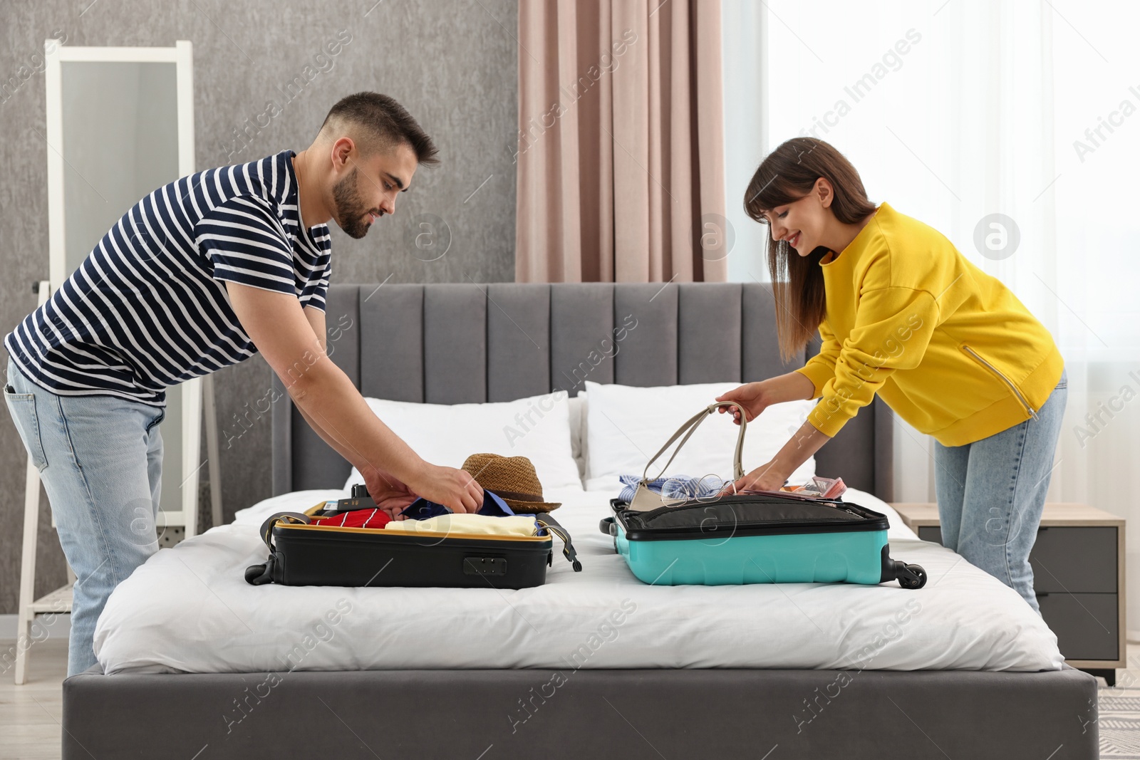 Photo of Couple packing suitcases for trip in bedroom