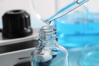 Photo of Dripping liquid from pipette into bottle in laboratory, closeup