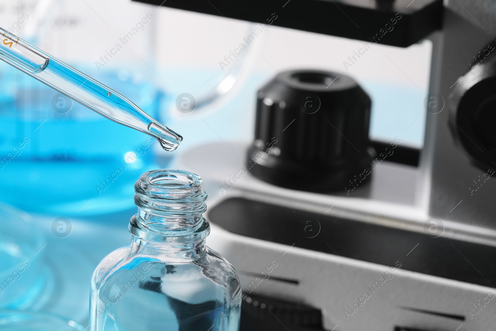 Photo of Dripping liquid from pipette into bottle in laboratory, closeup