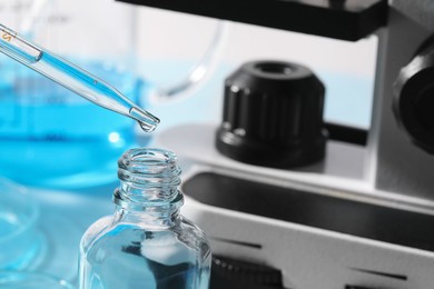 Photo of Dripping liquid from pipette into bottle in laboratory, closeup