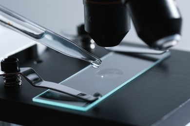 Dripping liquid from pipette onto glass slide on microscope, closeup